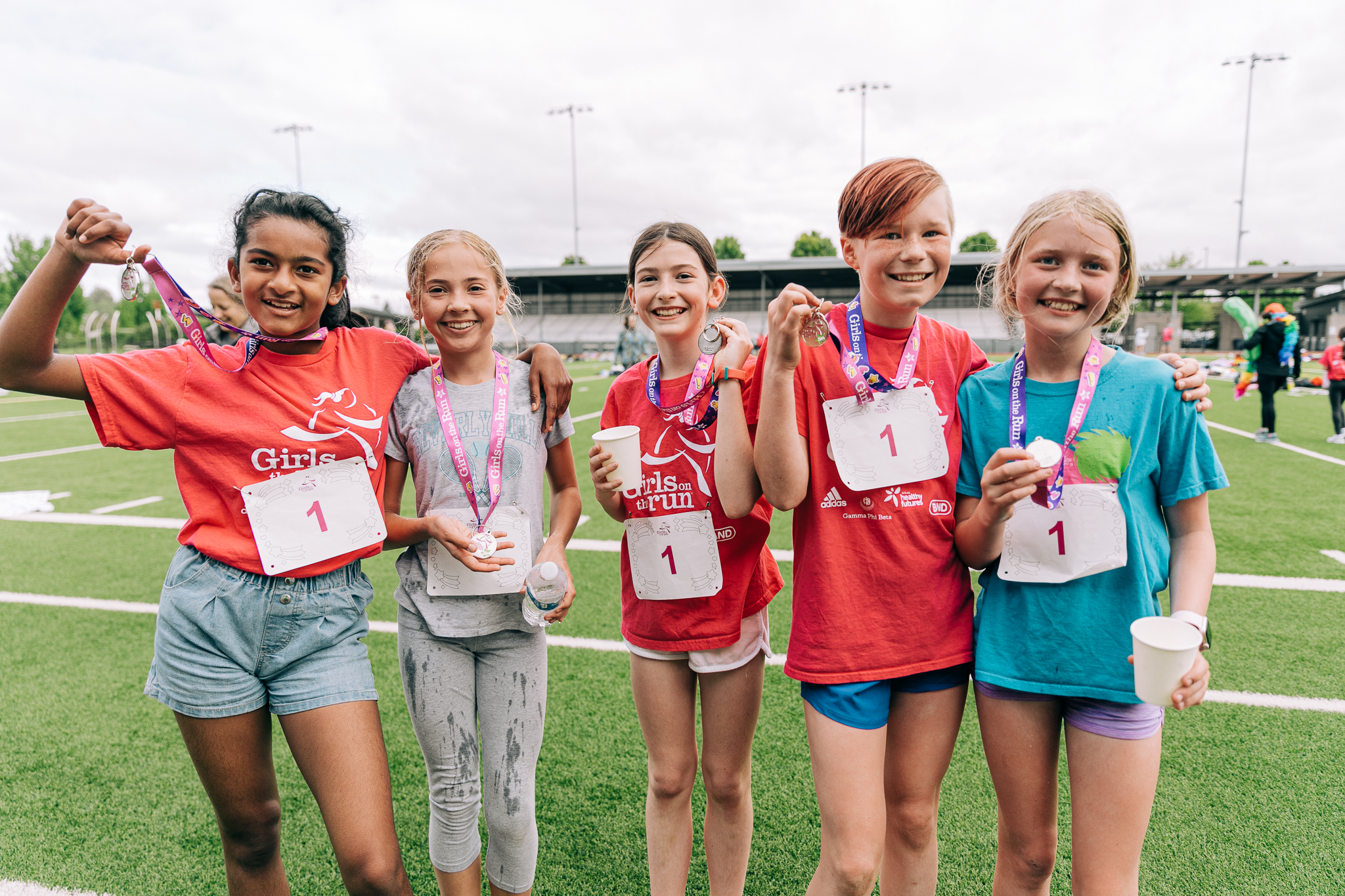 A group of GOTR participants from GOTR Puget Sound proudly holding up their medals after completing the 5K